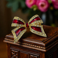 Vintage 1990s bow brooch in red enamel and gold-tone metal with pavé rhinestones, shown worn or displayed to highlight its elegant design and excellent condition.