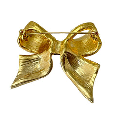 Vintage 1990s bow brooch in red enamel and gold-tone metal with pavé rhinestones, shown worn or displayed to highlight its elegant design and excellent condition.