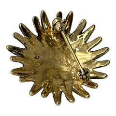 Vintage sunburst brooch with pink and clear rhinestones set in gold tone metal, featuring pointed petal-like rays and a central cluster of pink stones, photographed front and back to highlight its 1980s design and secure clasp.