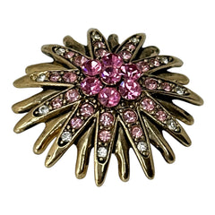 Vintage sunburst brooch with pink and clear rhinestones set in gold tone metal, featuring pointed petal-like rays and a central cluster of pink stones, photographed front and back to highlight its 1980s design and secure clasp.