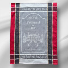 Provence tea towel featuring Châteauneuf-du-Pape winery chateau design with gray background and red and brown striped borders. Made of 100% cotton, ideal for wine-inspired kitchen decor and rustic elegance.