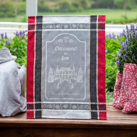 Provence tea towel featuring Châteauneuf-du-Pape winery chateau design with gray background and red and brown striped borders. Made of 100% cotton, ideal for wine-inspired kitchen decor and rustic elegance.