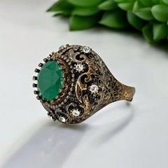 Vintage 1990s Turkish Sultan-style adjustable ring featuring a faceted emerald glass cabochon, clear rhinestones, and ornate antiqued bronze detailing in very good condition.