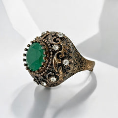 Vintage 1990s Turkish Sultan-style adjustable ring featuring a faceted emerald glass cabochon, clear rhinestones, and ornate antiqued bronze detailing in very good condition.