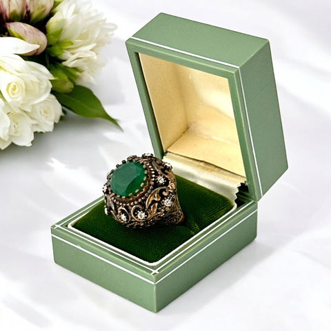 Vintage 1990s Turkish Sultan-style adjustable ring featuring a faceted emerald glass cabochon, clear rhinestones, and ornate antiqued bronze detailing in very good condition.