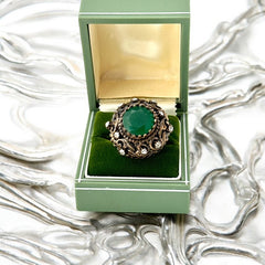 Vintage 1990s Turkish Sultan-style adjustable ring featuring a faceted emerald glass cabochon, clear rhinestones, and ornate antiqued bronze detailing in very good condition.