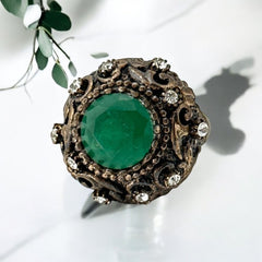 Vintage 1990s Turkish Sultan-style adjustable ring featuring a faceted emerald glass cabochon, clear rhinestones, and ornate antiqued bronze detailing in very good condition.