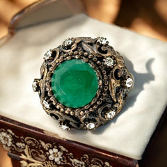 Vintage 1990s Turkish Sultan-style adjustable ring featuring a faceted emerald glass cabochon, clear rhinestones, and ornate antiqued bronze detailing in very good condition.