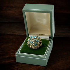 Vintage gold-tone dome cocktail ring featuring faux turquoise, peridot rhinestones, and faux seed pearls with a textured shank. Adjustable on one side and estimated from the 1990s, in good vintage condition.