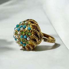 Vintage gold-tone dome cocktail ring featuring faux turquoise, peridot rhinestones, and faux seed pearls with a textured shank. Adjustable on one side and estimated from the 1990s, in good vintage condition.