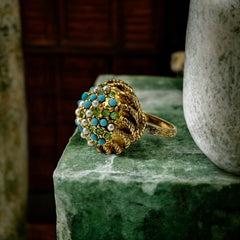 Vintage gold-tone dome cocktail ring featuring faux turquoise, peridot rhinestones, and faux seed pearls with a textured shank. Adjustable on one side and estimated from the 1990s, in good vintage condition.