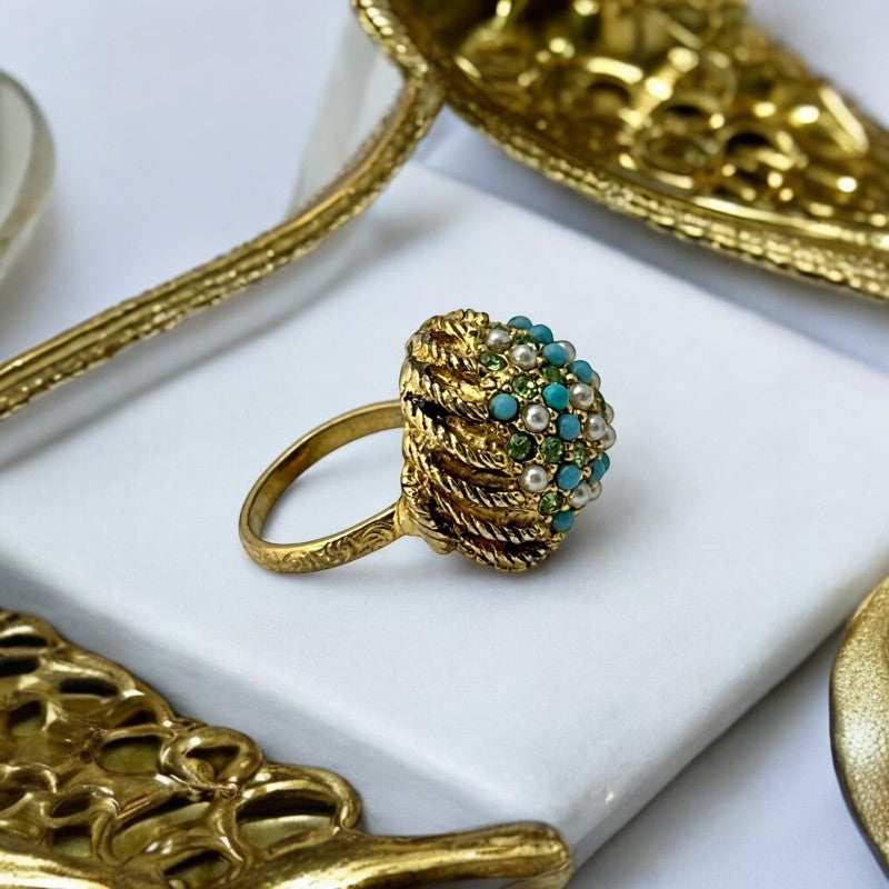 Vintage gold-tone dome cocktail ring featuring faux turquoise, peridot rhinestones, and faux seed pearls with a textured shank. Adjustable on one side and estimated from the 1990s, in good vintage condition.