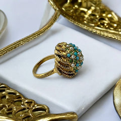 Vintage gold-tone dome cocktail ring featuring faux turquoise, peridot rhinestones, and faux seed pearls with a textured shank. Adjustable on one side and estimated from the 1990s, in good vintage condition.