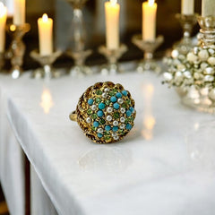 Vintage gold-tone dome cocktail ring featuring faux turquoise, peridot rhinestones, and faux seed pearls with a textured shank. Adjustable on one side and estimated from the 1990s, in good vintage condition.