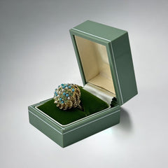 Vintage gold-tone dome cocktail ring featuring faux turquoise, peridot rhinestones, and faux seed pearls with a textured shank. Adjustable on one side and estimated from the 1990s, in good vintage condition.