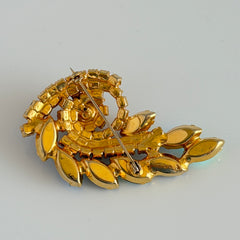 Gold‑tone vintage brooch with AB topaz, smoky, and clear rhinestones in a floral swirl shape.