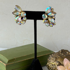 Vintage gold‑tone floral clip‑on earrings with iridescent AB marquise and round rhinestones reflecting rainbow hues.