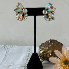 Vintage gold‑tone floral clip‑on earrings with iridescent AB marquise and round rhinestones reflecting rainbow hues.