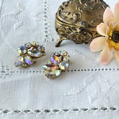 Vintage gold‑tone floral clip‑on earrings with iridescent AB marquise and round rhinestones reflecting rainbow hues.