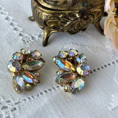 Vintage gold‑tone floral clip‑on earrings with iridescent AB marquise and round rhinestones reflecting rainbow hues.