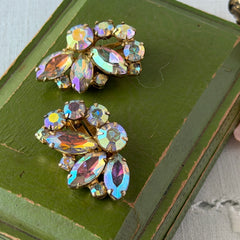 Vintage gold‑tone floral clip‑on earrings with iridescent AB marquise and round rhinestones reflecting rainbow hues.