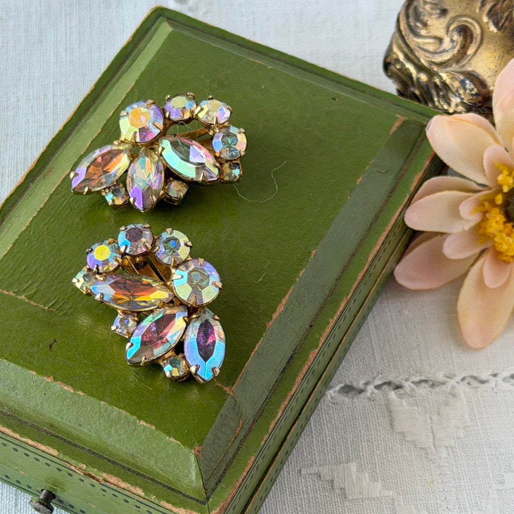 Vintage gold‑tone floral clip‑on earrings with iridescent AB marquise and round rhinestones reflecting rainbow hues.