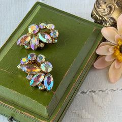 Vintage gold‑tone floral clip‑on earrings with iridescent AB marquise and round rhinestones reflecting rainbow hues.
