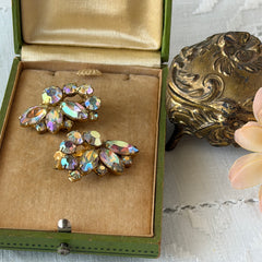 Vintage gold‑tone floral clip‑on earrings with iridescent AB marquise and round rhinestones reflecting rainbow hues.