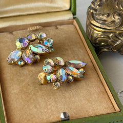 Vintage gold‑tone floral clip‑on earrings with iridescent AB marquise and round rhinestones reflecting rainbow hues.