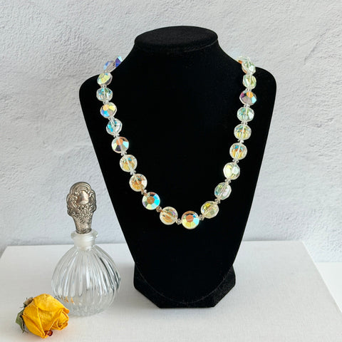 Vintage AB crystal coin necklace with large faceted iridescent beads, clear spacers, and an adjustable hook clasp, shown on a display stand and in close‑up views.