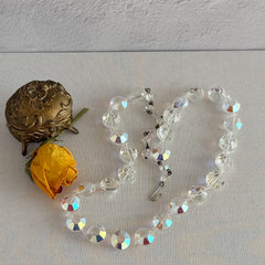 Vintage AB crystal coin necklace with large faceted iridescent beads, clear spacers, and an adjustable hook clasp, shown on a display stand and in close‑up views.