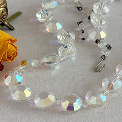 Vintage AB crystal coin necklace with large faceted iridescent beads, clear spacers, and an adjustable hook clasp, shown on a display stand and in close‑up views.