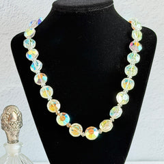Vintage AB crystal coin necklace with large faceted iridescent beads, clear spacers, and an adjustable hook clasp, shown on a display stand and in close‑up views.