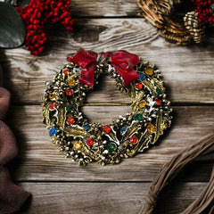 Vintage ART signed Christmas wreath brooch with red and white enamel, multicolor rhinestones, gold-tone openwork design, and red bow; mid-century holiday jewelry in very good condition.