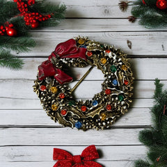 Vintage ART signed Christmas wreath brooch with red and white enamel, multicolor rhinestones, gold-tone openwork design, and red bow; mid-century holiday jewelry in very good condition.