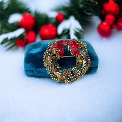 Vintage ART signed Christmas wreath brooch with red and white enamel, multicolor rhinestones, gold-tone openwork design, and red bow; mid-century holiday jewelry in very good condition.