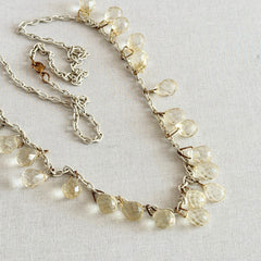 Vintage 1990s long necklace with acrylic faceted briolettes on a mixed‑metal chain, displayed with vintage props.
