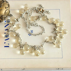 Vintage 1990s long necklace with acrylic faceted briolettes on a mixed‑metal chain, displayed with vintage props.