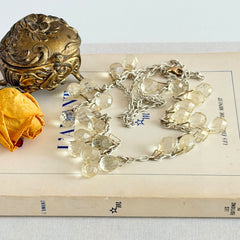 Vintage 1990s long necklace with acrylic faceted briolettes on a mixed‑metal chain, displayed with vintage props.