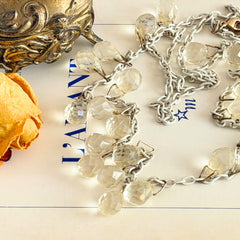 Vintage 1990s long necklace with acrylic faceted briolettes on a mixed‑metal chain, displayed with vintage props.