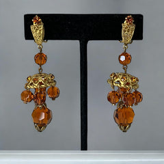 Vintage gold-tone clip-on earrings with honey topaz faceted crystals and ornate filigree dangle design.