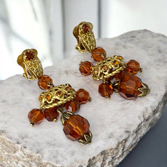 Vintage gold-tone clip-on earrings with honey topaz faceted crystals and ornate filigree dangle design.