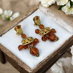 Vintage gold-tone clip-on earrings with honey topaz faceted crystals and ornate filigree dangle design.