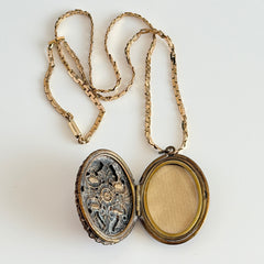 Vintage brass locket pendant with a warm glass cabochon, floral detailing, and a signed Krementz gold‑plated serpentine chain.