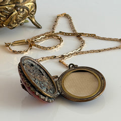 Vintage brass locket pendant with a warm glass cabochon, floral detailing, and a signed Krementz gold‑plated serpentine chain.