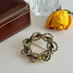 Vintage gold tone wreath brooch with amethyst, peridot, and blue rhinestones, shown in various decorative arrangements.