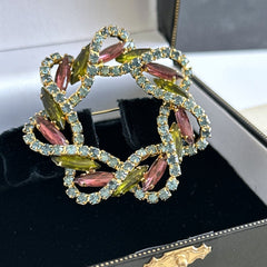 Vintage gold tone wreath brooch with amethyst, peridot, and blue rhinestones, shown in various decorative arrangements.