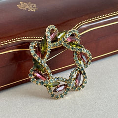 Vintage gold tone wreath brooch with amethyst, peridot, and blue rhinestones, shown in various decorative arrangements.