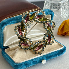 Vintage gold tone wreath brooch with amethyst, peridot, and blue rhinestones, shown in various decorative arrangements.