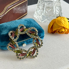 Vintage gold tone wreath brooch with amethyst, peridot, and blue rhinestones, shown in various decorative arrangements.